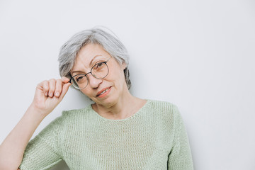Elderly woman posing in a studio against a light background with copy space