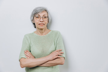 Elderly woman posing in a studio against a light background with copy space