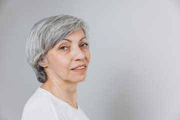 Elderly woman posing in a studio against a light background with copy space