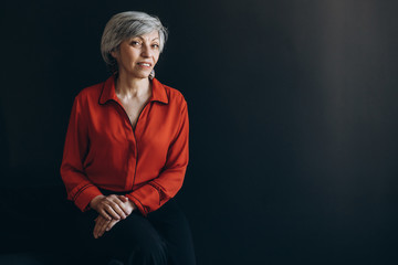 Elderly woman dressed in red against a dark background