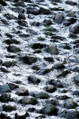 Water flowing through a waterway laid with round stones on the bottom of the river
