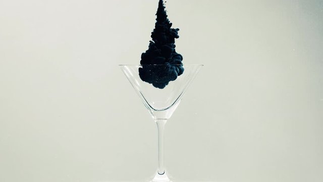 Cocktail glass in water with black paint project on it on a white background