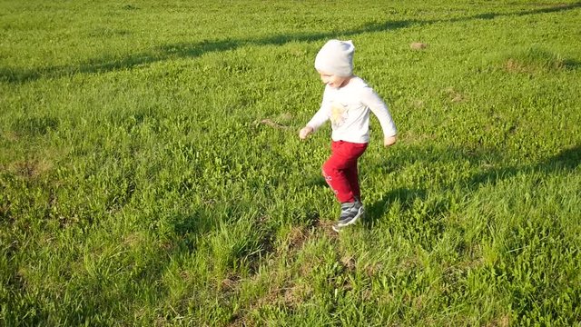 A lovely little boy runs along the grass and stumbles