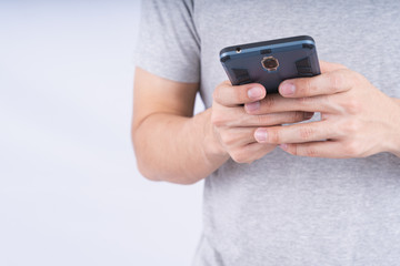Yong man wearing grey t-shirt holding smartphone on white background. Technology concept.