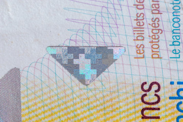 Detail of 10 CHF Swiss franc banknote.  Swiss cross printed with a special ink and changes colour depending on how the light falls on the banknote.