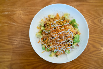 Top view image of Avocado salad with crunchy noodles on top.