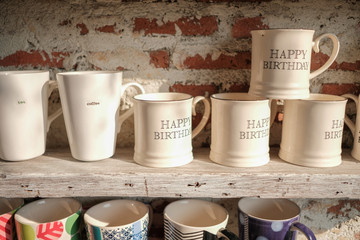 White mug cups placed on the wood shelves and red brick wall background