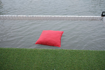 Red pillow placed on net over the river. Vacation net seat over the river.