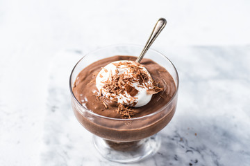 Vegan avocado, banana and cocoa mousse. Topped with coconut whipped cream and dark chocolate. White background