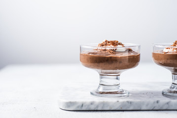 Vegan avocado, banana and cocoa mousse. Topped with coconut whipped cream and dark chocolate. White background