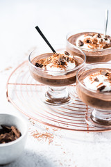 Vegan avocado, banana and cocoa mousse. Topped with coconut whipped cream and dark chocolate. White background