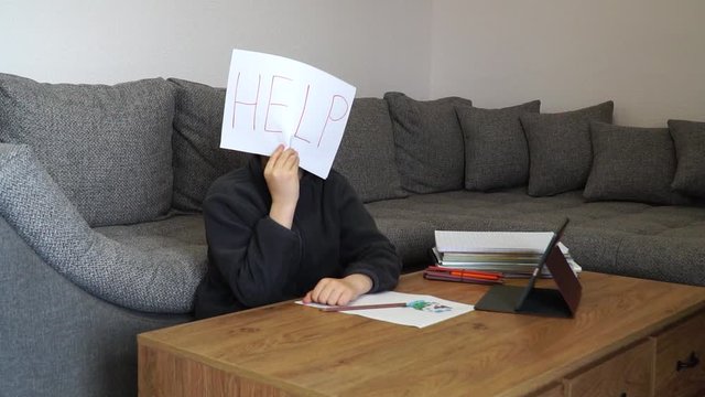 Learning difficulties. Sad tired frustrated boy with many books and holding paper with word Help. Education concept.