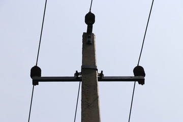 Electric pole made of concrete carrying 3 wires which gives current supply for homes