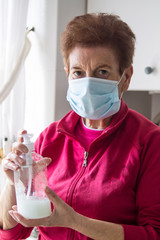 senior woman with medical mask and plastic dispenser with soap to clean hands, preventive against viruses and infections