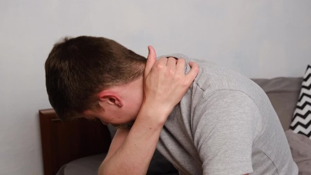 Side view of upset tired young man wear t-shirt feels pain in neck in morning after sleeping, awaken in bad temper having painful sudden ache or stiffness. Fibromyalgia concept
