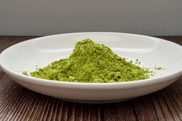 matcha green tea powder in bowl on wooden table. Top view. Space for text. healthy food concept