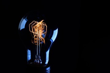 retro Edison lamp with incandescent tungsten filament close-up on a black background. Copy space, space for text