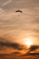 Vue verticale d'une petite silhouette d'un paramoteur en vol au coucher du soleil