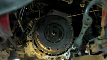 Fototapeta premium Mechanic is uninstalling a car clutch. Car service worler with diry hands taking off car clutch close up.