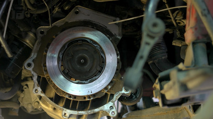 Fototapeta premium Mechanic installing bolts on a car clutch. Repairman with elecrtrical screwdriver close up.