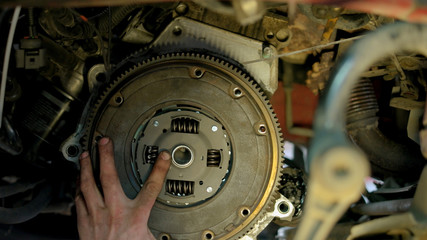 Car mechanic is unscrewing clutch. Car service worker with diry hands using electrical screwdriver to unscrew car clutch.