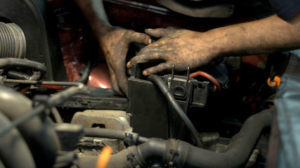 Fototapeta na wymiar Mechanic with dirty hands uninstalling and fixing car engine details. Professinal repairman in a car service center repairing a car motor.
