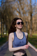 Beautiful athletic girl in sport clothes and glasses on the playground. Healthy lifestyle. Soft selective focus.