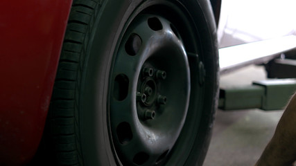 Fototapeta premium Tightening the nuts in the car wheel. Close-up wheel and hands of mechanics