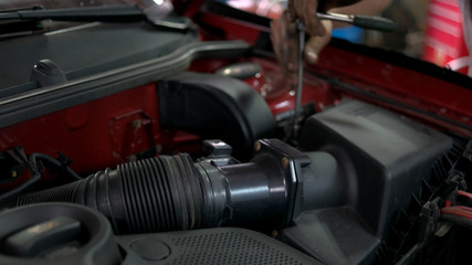 Repairman unscrewing and withdrawing big car engine detail. Close up dirty male hands of car...
