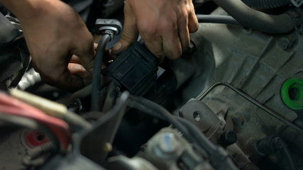 Fototapeta na wymiar Repairman hands screwing car enging details. Close dirty male hands of a car service worker.