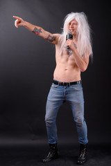 Full body shot of happy rebellious man as punk rocker with wig singing