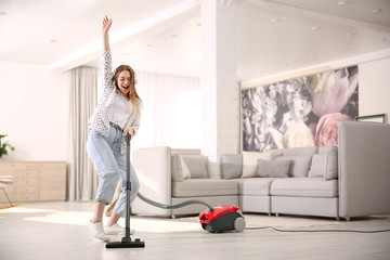 Young woman having fun while vacuuming at home