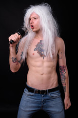 Punk rocker man wearing wig against black background