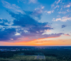 Sunset sky with clouds. The sun shines on the clouds after sunset. Beautiful nature with glam and forest. Aerial view