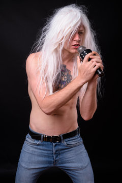 Punk rocker man wearing wig against black background