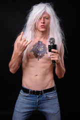 Punk rocker man wearing wig against black background