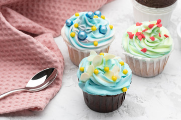 Colorful cupcakes decorated by caramel candies on grey table with pink napkin and spoon