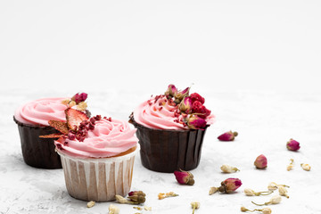 Colorful cupcakes decorated by sublemented berries  and buttons of dry flowers  on white background. Horizontal with space for text