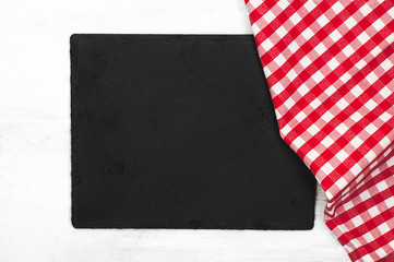 Black blank slate board and a red checkered tablecloth on a white. Mockup for food background. Kitchen utensils