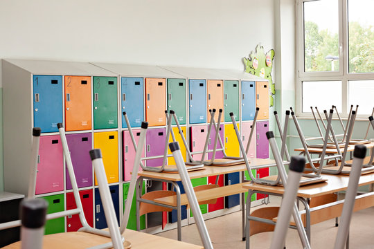 Empty classroom with colorful lockers and raised chairs on the tables - back to school