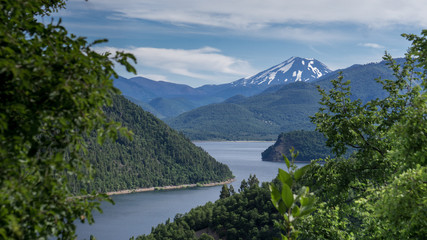 Fototapeta na wymiar Patagonia, lake view with green trees and a volcano on the background 