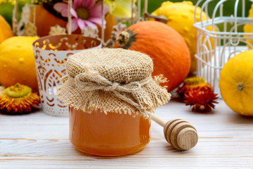 Glass jar of honey and pumpkins on the table.