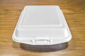 Close up of big square white foam box on brown wooden table.