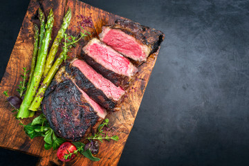 Barbecue dry aged wagyu entrecote beef steak with lettuce and green asparagus as top view on an old...