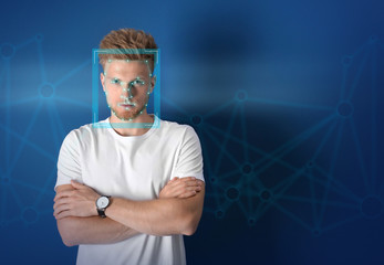Facial recognition system. Young man with scanner frame and digital biometric grid on blue...