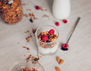 Homemade granola with yogurt and fresh raspberries on a light background.