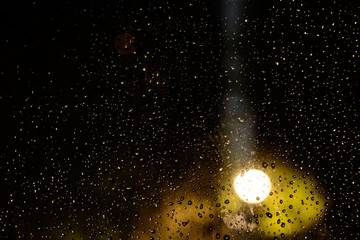 Night. raindrops on dark glass illuminated by a lantern. Concept - background, image of the starry...