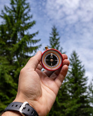 Compass in the hands in the Carpathian forest. Traveling in the mountains..