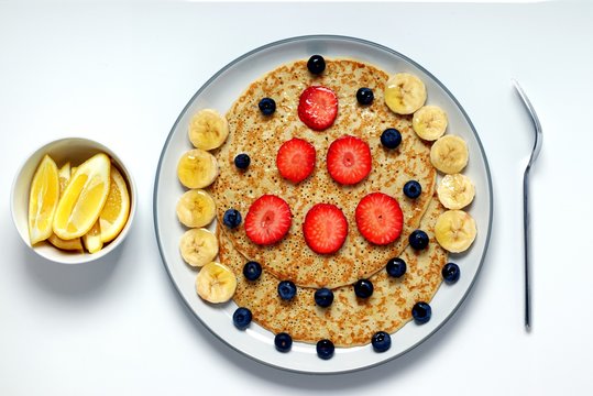 Flat lay image of some pancakes,with some fruit,shot on a white surface.