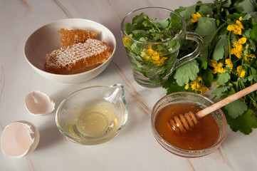 Natural home skin care. Ingredients of a face mask. Celandine decoction, honey and egg white on a pastel green marble background. Selective focus.
